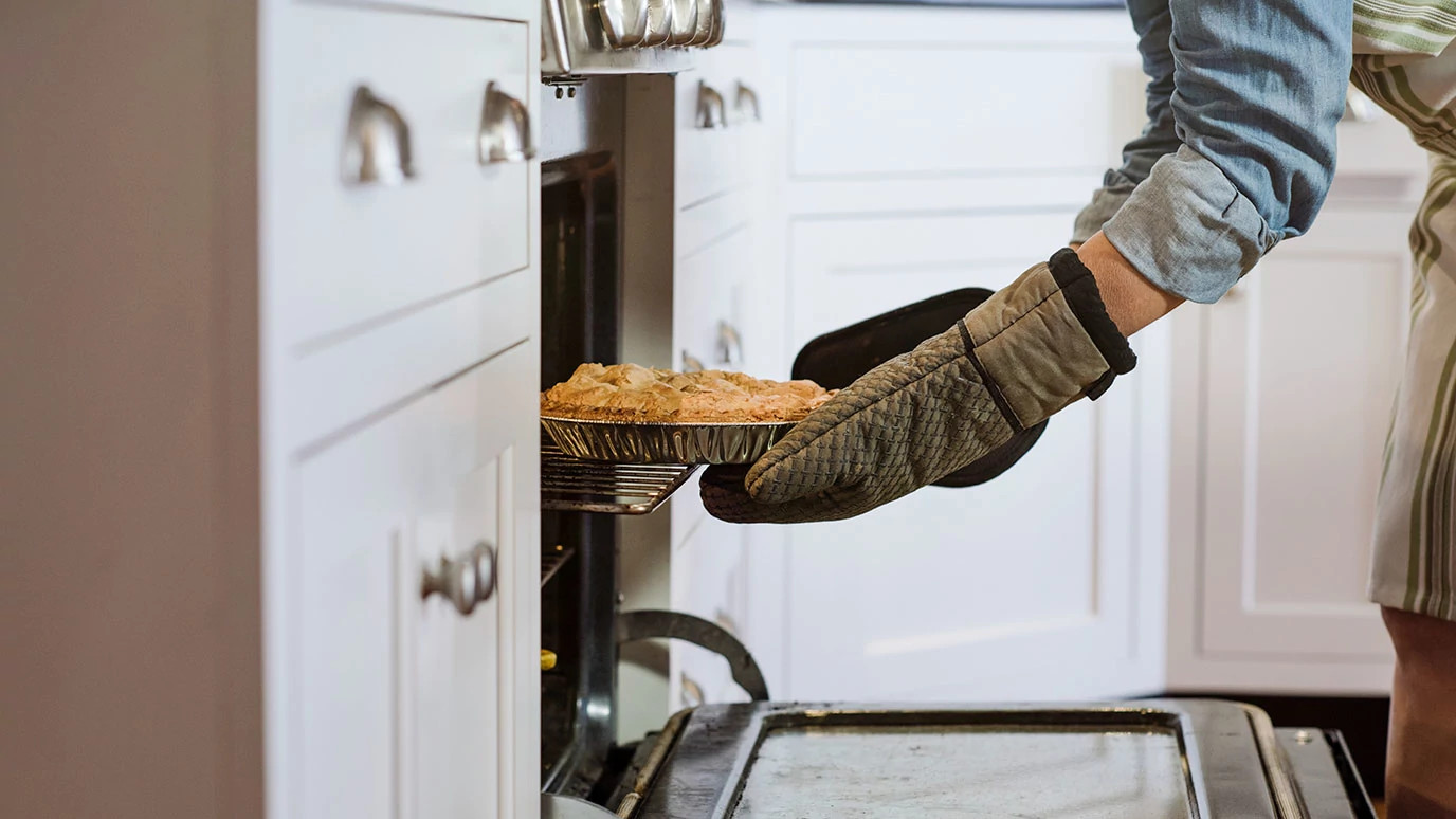 Person putting pie into oven